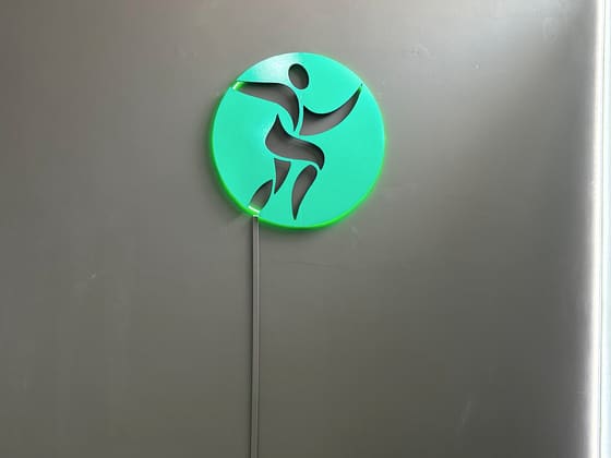 Logo da clínica em verde, na parede escura da recepção.