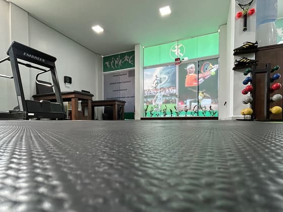 Área de treino com esteira, piso emborrachado e bolas de exercício.