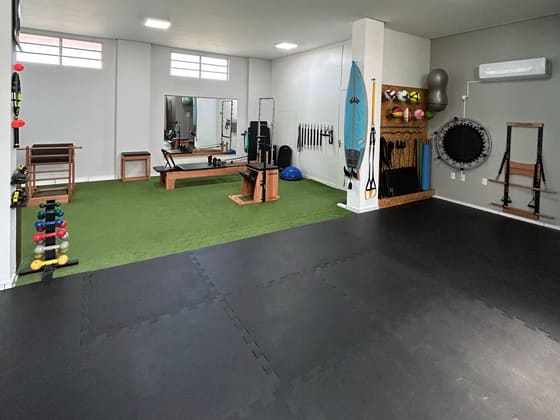 Área de treino da clínica, com piso emborrachado, grama sintética, bolas e aparelhos.
