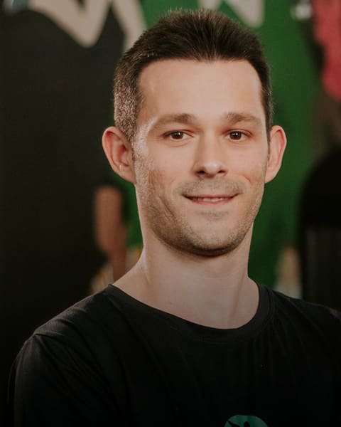 Dr. William Cardoso, fisioterapeuta, sorrindo, de camiseta preta com o logo da clínica.